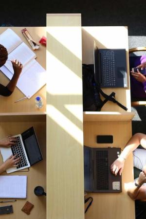 four students seated at study desks divided by partition